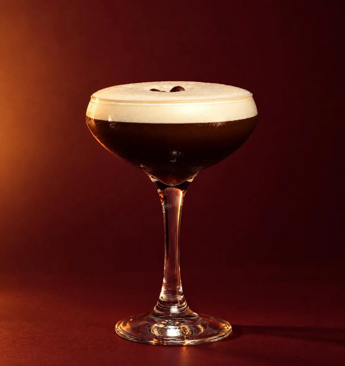 Espresso martini en copa coupé sobre fondo rojo