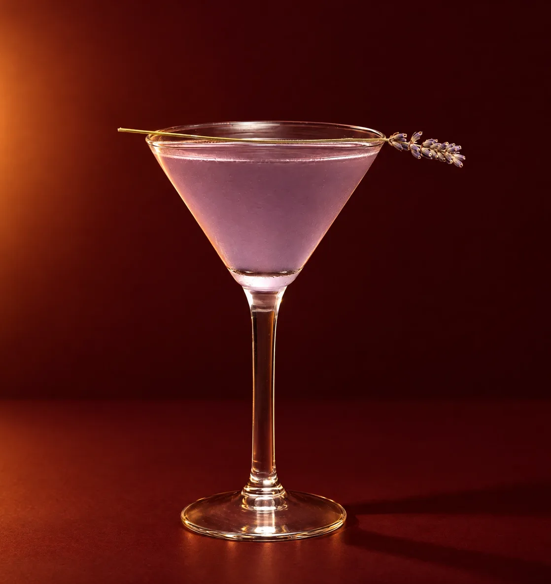 Martini de lavanda con una ramita de lavanda sobre fondo rojo