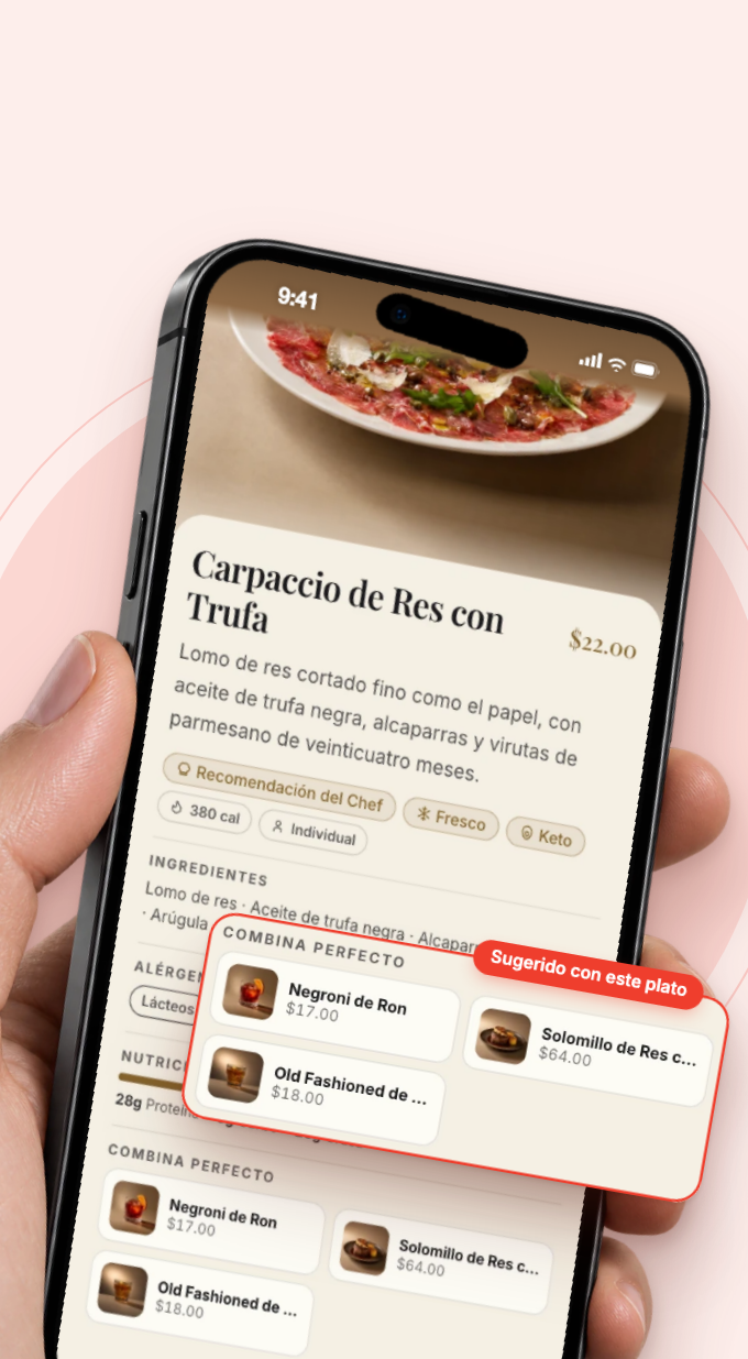Mano sosteniendo un teléfono con el Carpaccio de Res con Trufa; la sección Combina perfecto (Negroni de Ron $17.00, Solomillo de Res $64.00, Old Fashioned $18.00) aparece ampliada sobre el teléfono con la etiqueta Sugerido con este plato